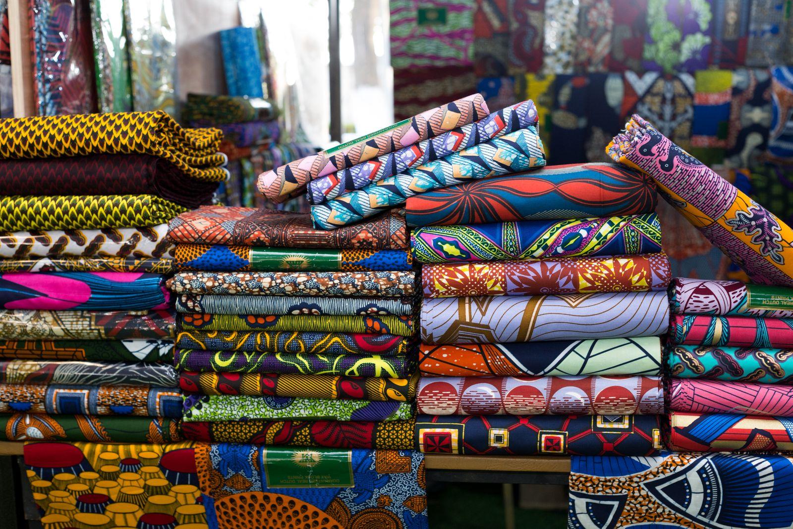 Stacked bolts of brightly patterned African wax-print fabric on a market table