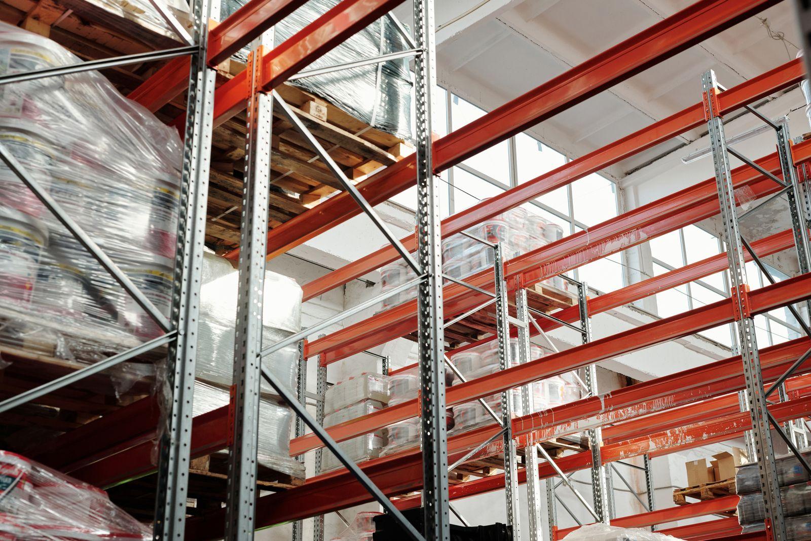 Warehouse interior with orange pallet racking and wrapped pallets